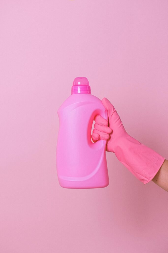 This is a featured blog image with a hot pink background, a picture of a basket of dorm cleaning supplies, and pink text overlay that says "the best dorm cleaning supplies".